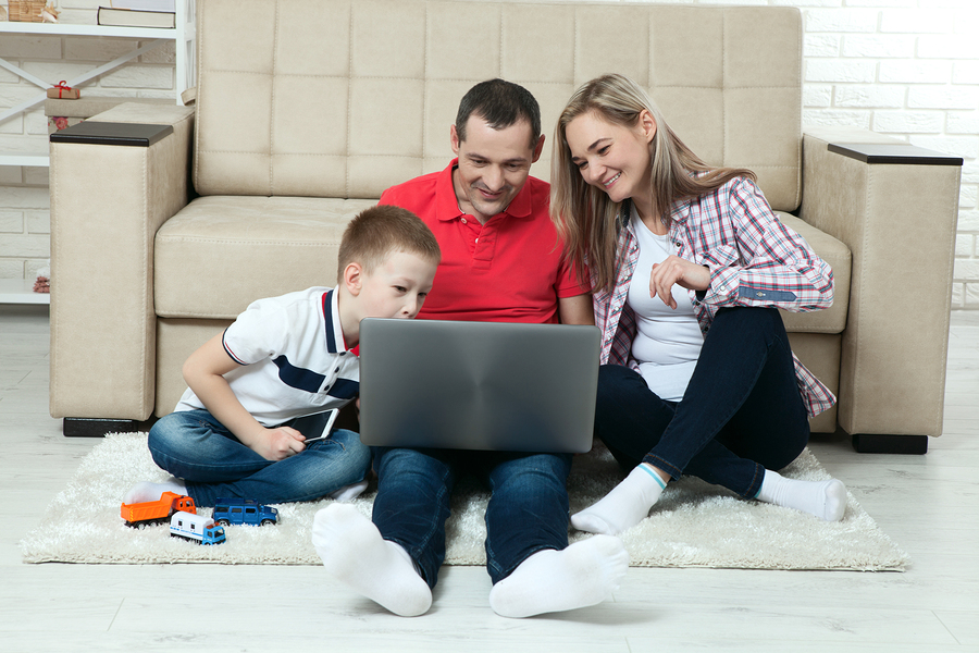 Familie sitzt zuhause am Boden mit Tablet